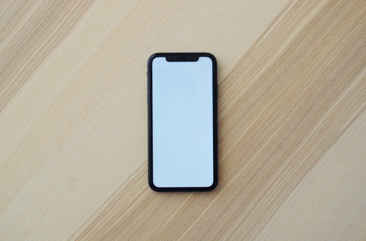 a phone laying down on a flat surface displaying a white screen